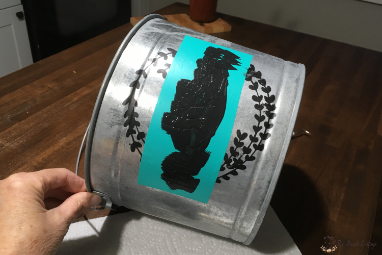 painting a flower market stencil onto a galvanized bucket