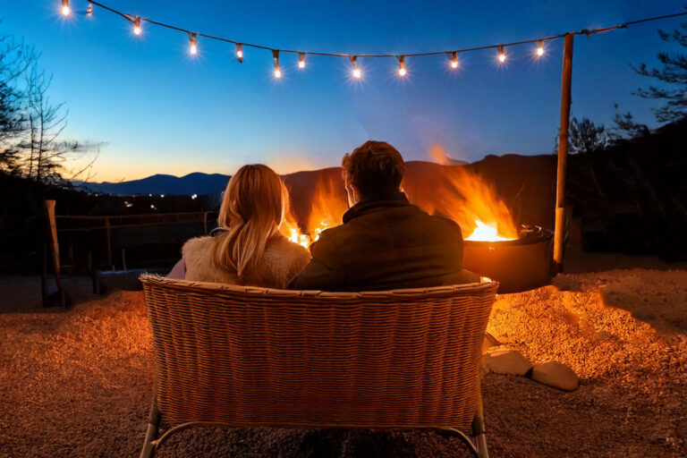 Couple enjoying warm outdoor seating by fire pit at twilight